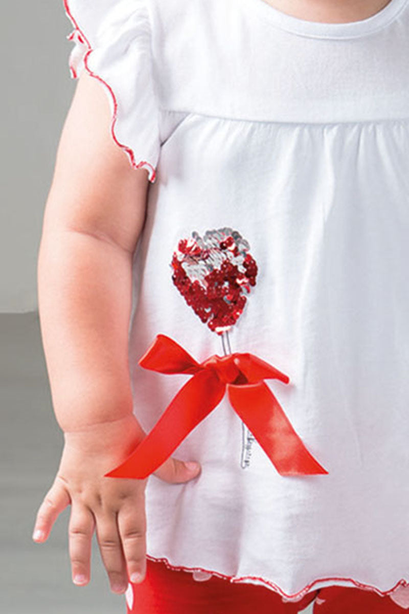 Completo: t-shirt in cotone con taglio carrè, paillettes reversibili e fiocco applicato + pinocchietto in cotone elasticizzato fantasia cuori con fiocchi sul fondo